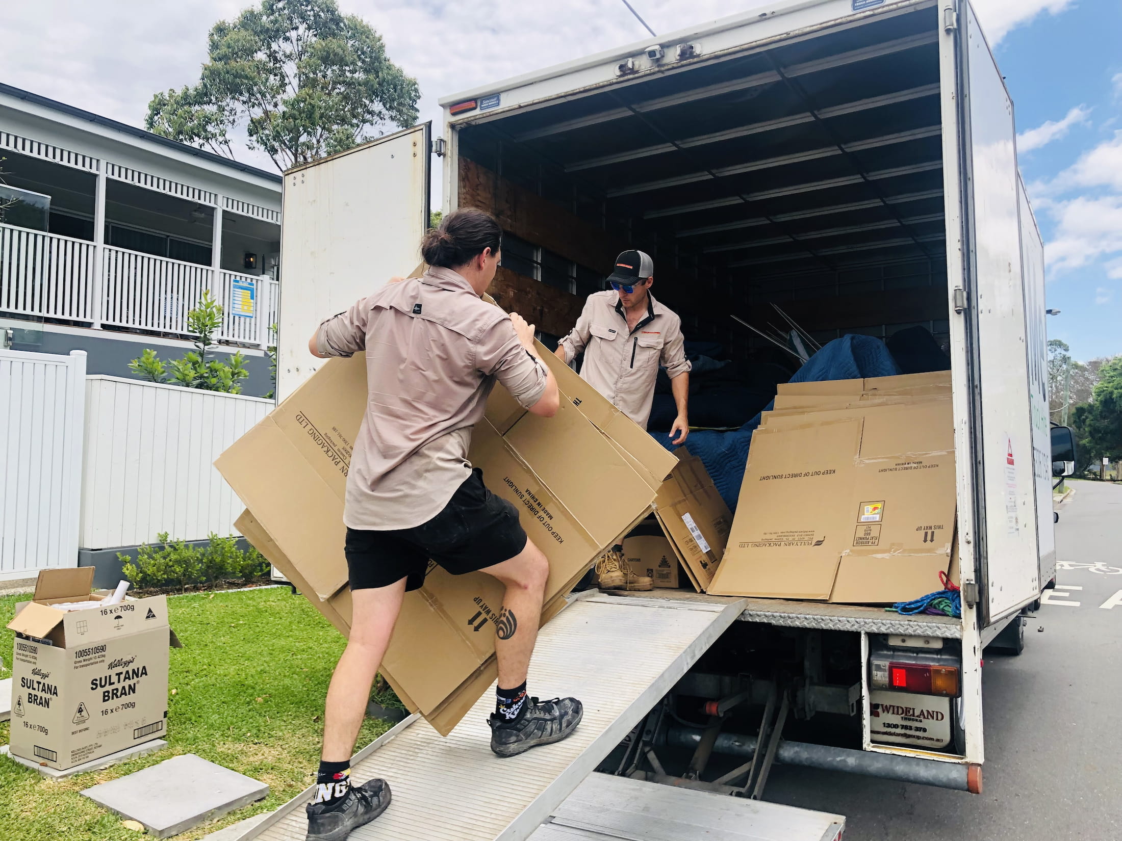 two men lifting carboard onto a truck