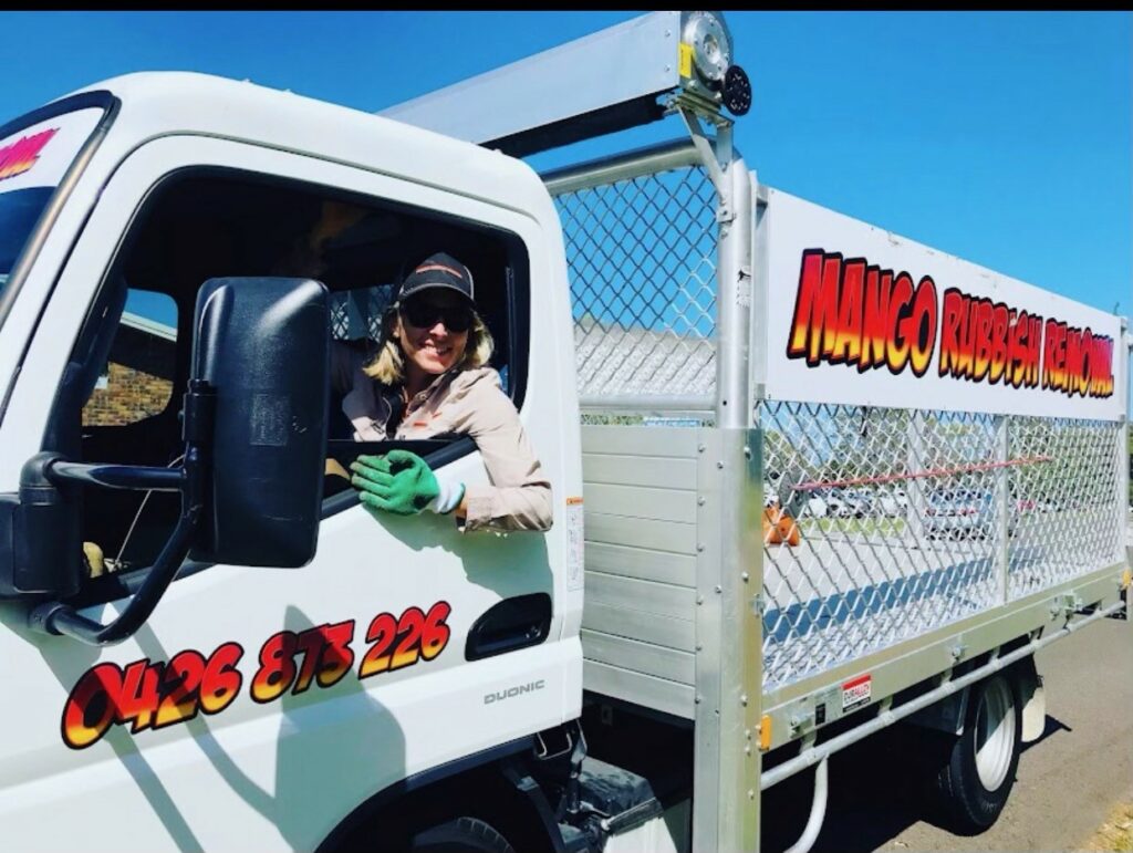 women leaning out the window of a rubbish removal truck
